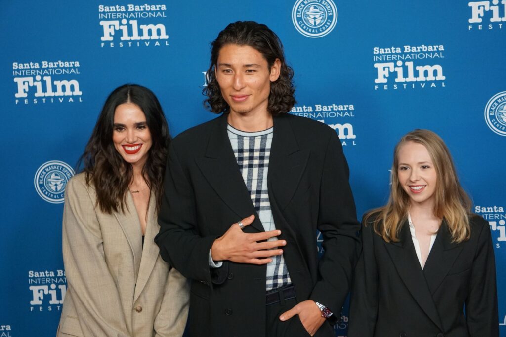 Three people pose for photo on red carpet of film festival