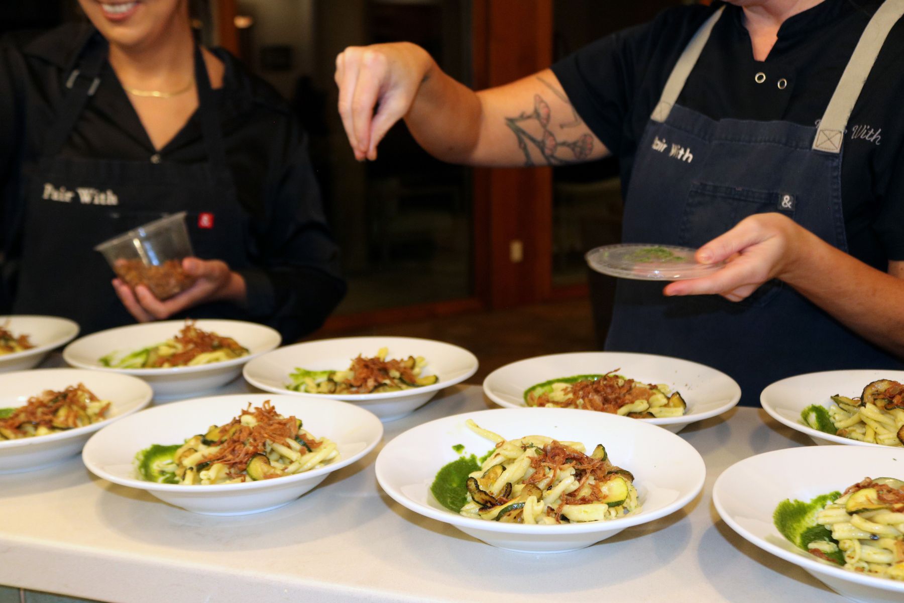 Photo of pasta plates receiving garnish