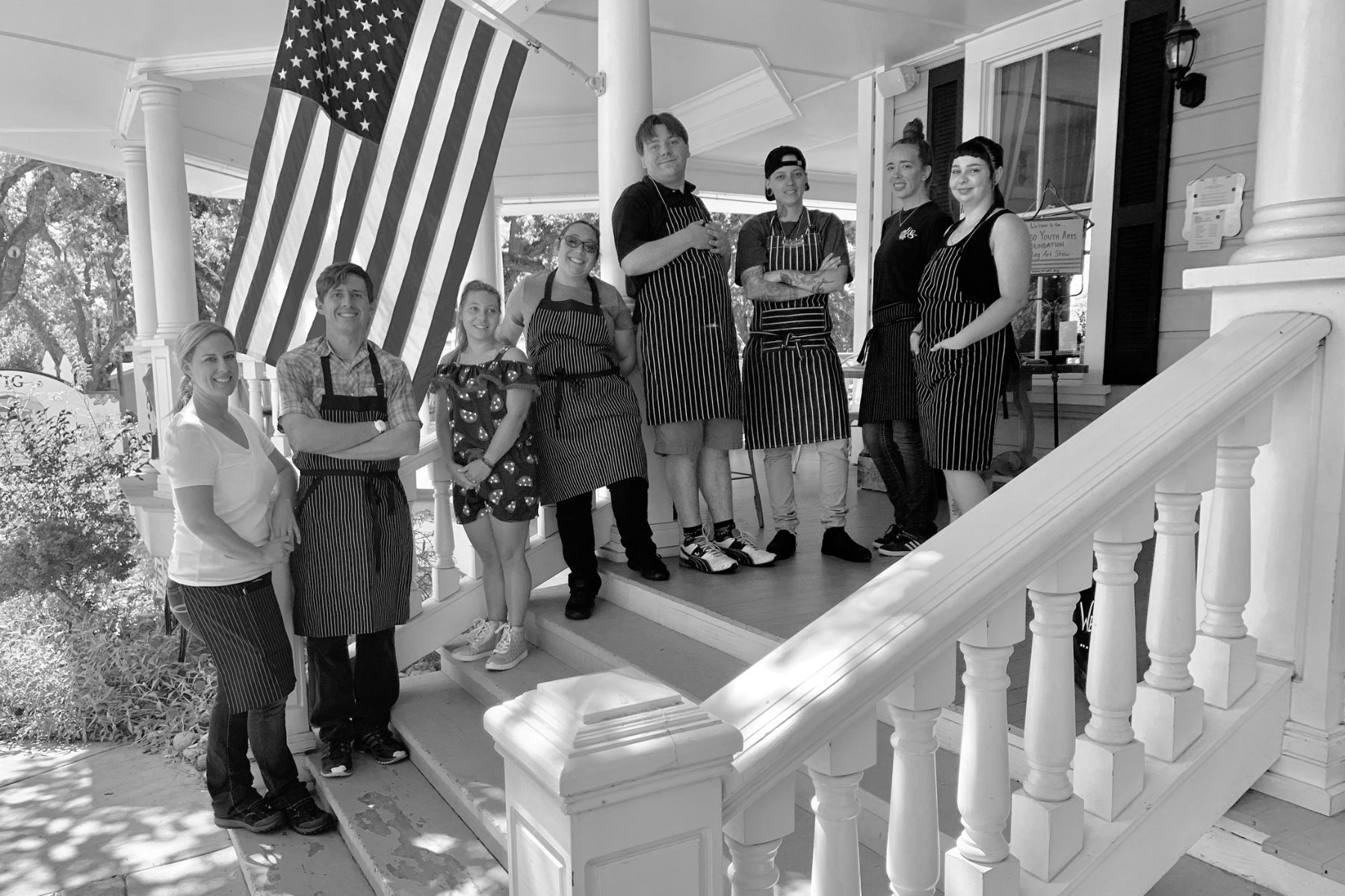 Group poses for photo on porch, in black and white.