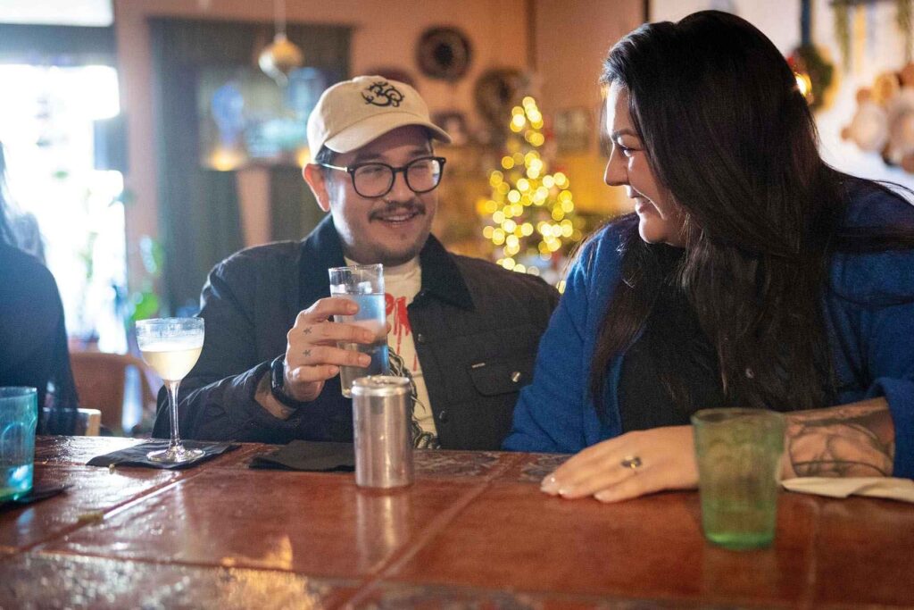 Guests Josh and Abigail cozy up to the bar with drinks, both alcoholic and spirit-free.